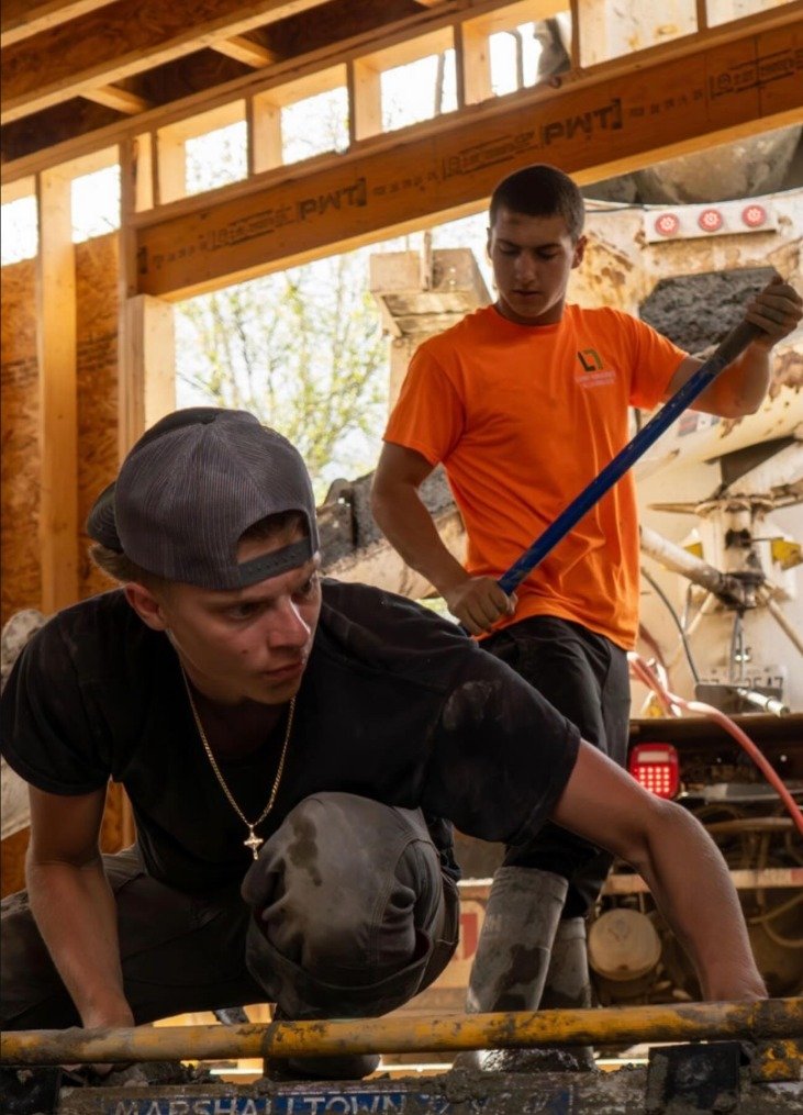 Interior foundation pour inside a new framed build, crew guiding the chute