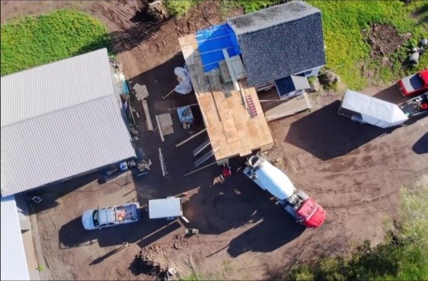 Aerial view of an active Lush job site — mixer truck, framing deck, and staging