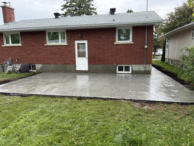Stamped concrete patio behind a brick bungalow