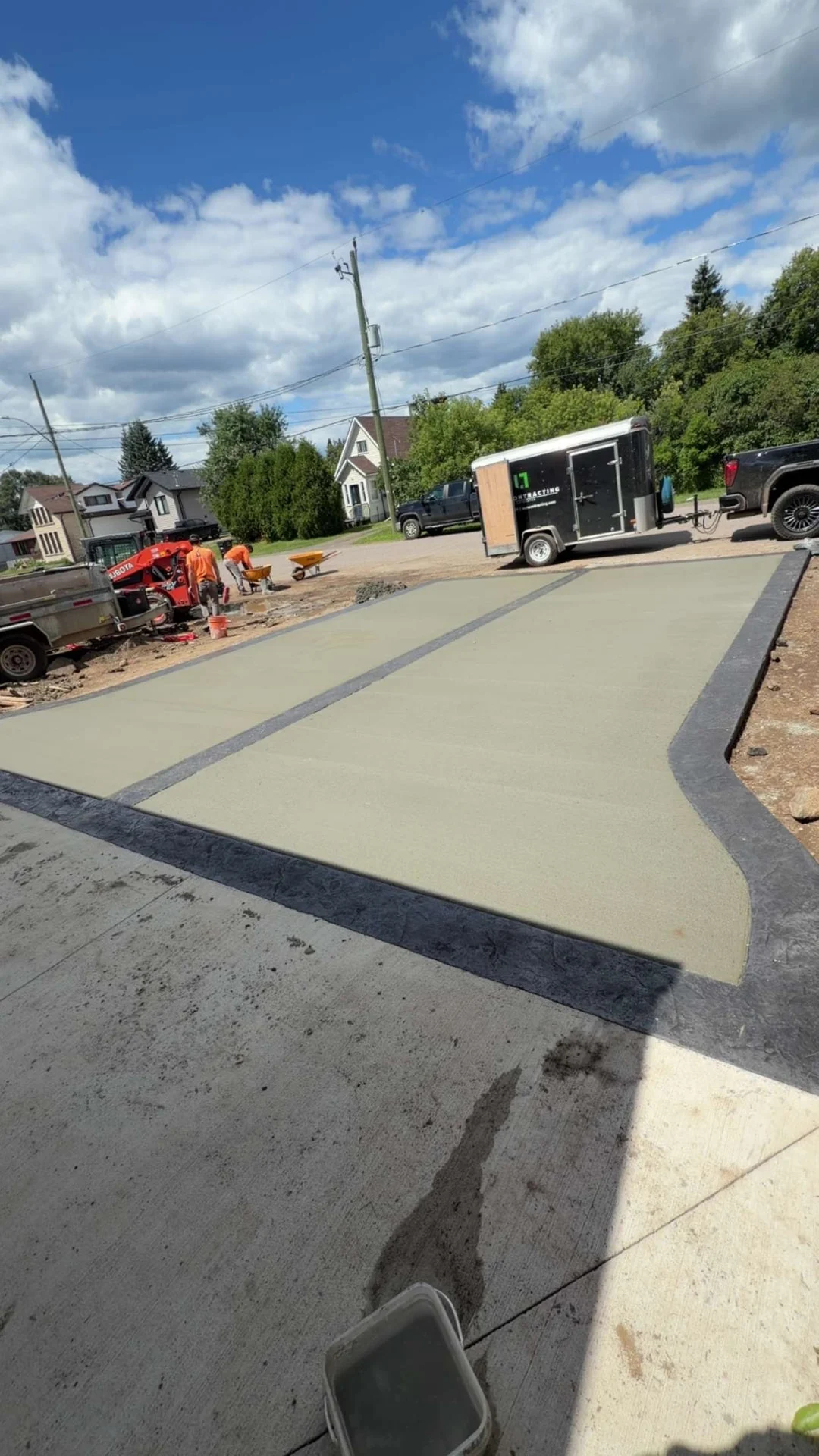Wide driveway pour with charcoal stamped border and Lush trailer on site